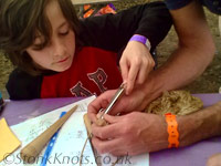 Using a ropeworking tool (splicing fid) to form a Turks' Head around a cork for a floating keyring, Wychwood 2012